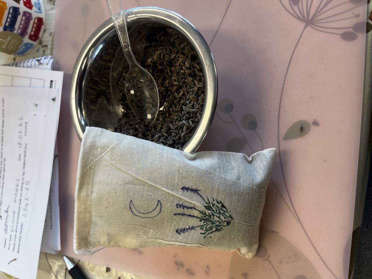 Ellie's handmade lavender sachet from her Junior Herbalist Club course leader training, with embroidered lavender sprig, alongside the bowl of dried lavender used in the session